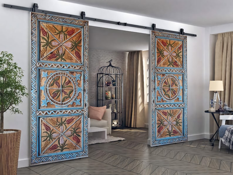 May include: Two wooden barn doors with a distressed, hand-painted design. The doors feature a repeating pattern of flowers and geometric shapes in shades of blue, orange, and green. The doors are mounted on a black sliding track.