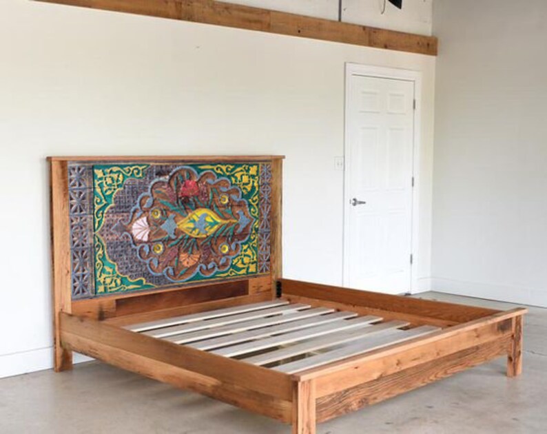 Puede incluir: Un marco de cama de madera con una cabecera de dise&ntilde;o colorido. La cabecera presenta un dise&ntilde;o geom&eacute;trico con tonos de verde, azul, amarillo y rojo. El marco de la cama est&aacute; hecho de madera reciclada y tiene un acabado natural.