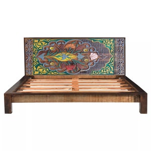 Puede incluir: Un marco de cama de madera con una cabecera tallada que presenta un dise&ntilde;o floral colorido. La cabecera est&aacute; pintada en tonos de azul, verde, amarillo y rojo. El marco de la cama tiene una base de listones.