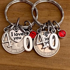 May include: Two silver-toned metal keychains featuring a circular coin base with the text 'DEI GRATIA'. Each keychain includes a heart-shaped charm engraved with 'I love you', the number '40' in large silver digits, and a small round red crystal charm.