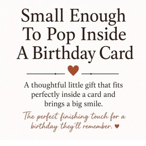 May include: A white rectangular sign with dark brown text that reads: Small Enough To Pop Inside A Birthday Card. Below this is a small brown heart, followed by the text: A thoughtful little gift that fits perfectly inside a card and brings a big smile. The perfect finishing touch for a birthday they'll remember, ending with a small brown heart.