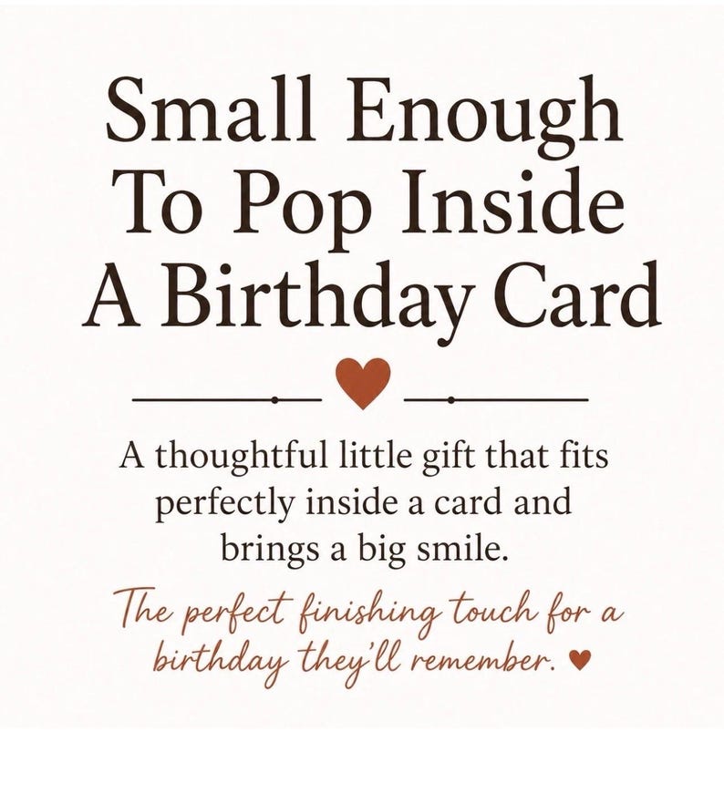 May include: A white rectangular sign with dark brown text that reads: Small Enough To Pop Inside A Birthday Card. Below this is a small brown heart, followed by the text: A thoughtful little gift that fits perfectly inside a card and brings a big smile. The perfect finishing touch for a birthday they'll remember, ending with a small brown heart.