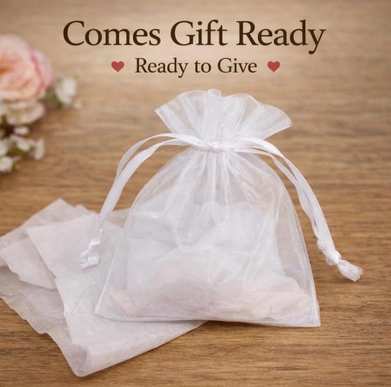 Puede incluir: Una bolsa de organza blanca transparente con cierre de cord&oacute;n fruncido. El texto sobre la bolsa dice "Comes Gift Ready" y "Ready to Give" con peque&ntilde;os iconos de corazones rojos a ambos lados de la segunda l&iacute;nea de texto.