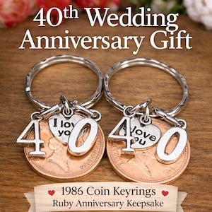 Può includere: Due portachiavi argentati con la scritta "40th Wedding Anniversary Gift". Ogni portachiavi presenta una moneta con i numeri "4" e "0", un ciondolo a forma di cuore con "I love you" e un anello argentato. È visibile anche il testo "1986 Coin Keyrings".