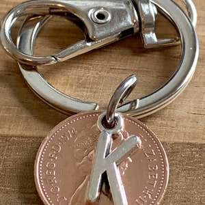 Llavero con dije de regalo de cumpleaños personalizado con forma de centavo de la suerte en bolsa de regalo para ella. Elija su año de nacimiento y su letra inicial en el cuadro desplegable