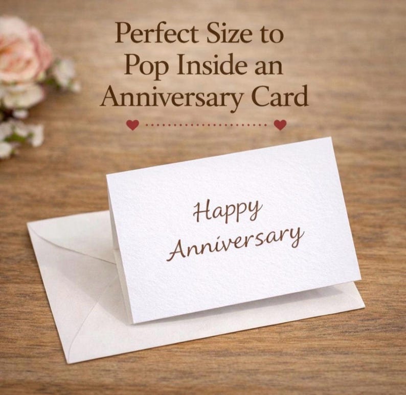 Puede incluir: Una peque&ntilde;a tarjeta blanca doblada con el texto Happy Anniversary en fuente cursiva marr&oacute;n, descansando sobre un sobre blanco a juego. El texto sobre la tarjeta dice Perfect Size to Pop Inside an Anniversary Card con dos peque&ntilde;os corazones rojos.