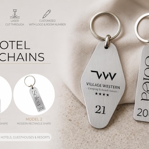 May include: Silver hotel keychains with a diamond and rectangle shape. The diamond-shaped keychain has the text "Village Western - Camping & Ranch Resort" and the number "21". The rectangle keychain has the name "Solea" and the number "206".