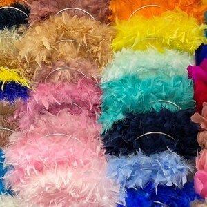 May include: A vibrant display of feather boas in various colors, including pink, blue, yellow, and orange. Each boa is arranged in a circular shape, showcasing the fluffy texture and rich hues. The image highlights the diversity of colors and the soft, voluminous nature of the feather boas.