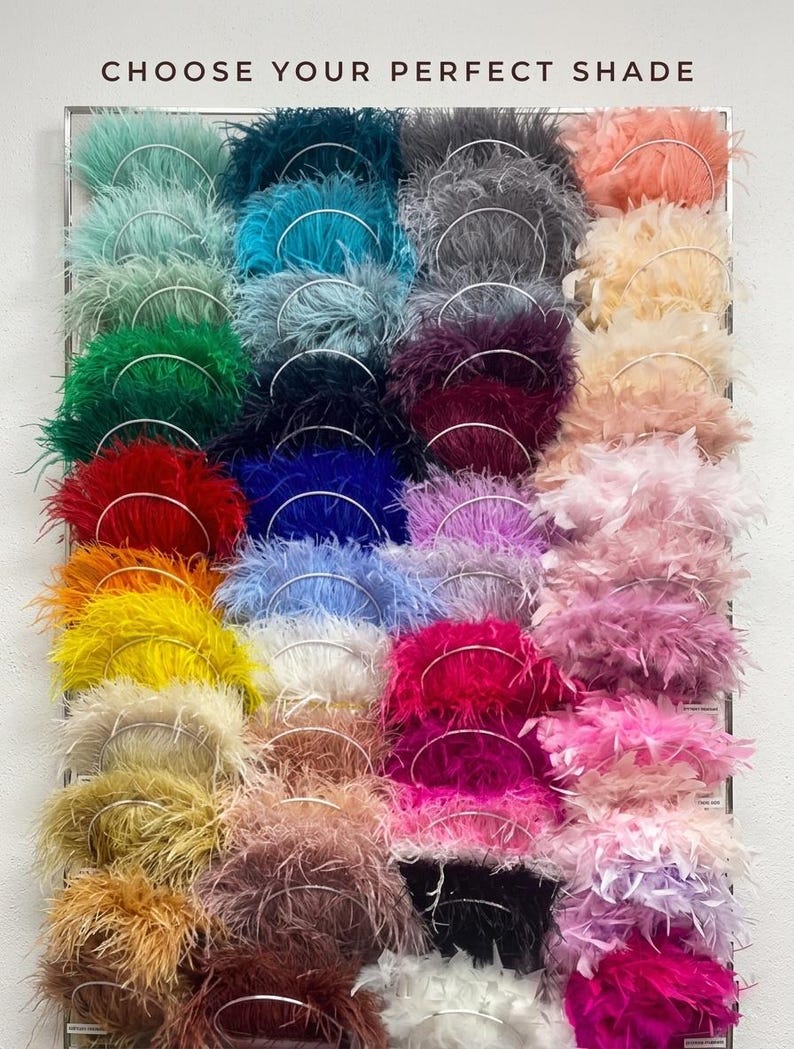 May include: A display of colorful feather boas in various shades, including teal, emerald green, red, and pink. The text "CHOOSE YOUR PERFECT SHADE" is at the top. Each boa is attached to a silver wire ring.