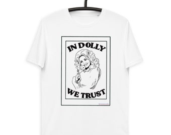 Könnte beinhalten: Ein weißes T-Shirt mit kurzen Ärmeln und einer schwarz-weißen Grafikillustration einer Frau mit voluminösem Haar. Der Text "IN DOLLY WE TRUST" ist in fetten schwarzen Großbuchstaben über und unter dem Porträt gedruckt.