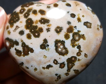 May include: A heart-shaped, polished stone with a white and brown speckled pattern. The stone has a smooth, glossy finish.