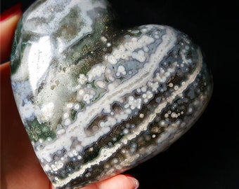 May include: A heart-shaped green, white and black agate stone with a swirling pattern of white and black lines and white dots.