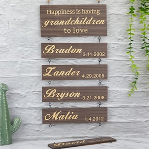 May include: Wooden signs with the text "Happiness is having grandchildren to love" and the names of grandchildren with their birth dates: Bradon 3.11.2002, Lander 4.29.2005, Bryson 3.21.2008, Malia 1.4.2012, and David.
