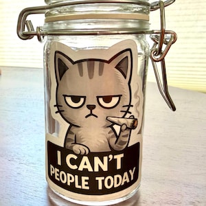 May include: A clear glass jar with a metal clasp and a cartoon cat sticker. The cat is gray with a grumpy expression and a lit cigarette. The sticker reads "I CAN'T PEOPLE TODAY" in white text on a black background.