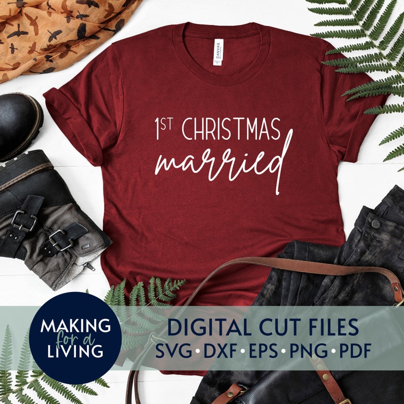 May include: A red t-shirt with the text "1st Christmas married" in white lettering. The shirt is lying flat on a white surface with other items around it.