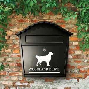 Puede incluir: Buzón negro con una silueta blanca de un perro y el texto "WOODLAND DRIVE" en la parte delantera.