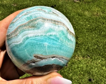 May include: A blue and brown sphere with a swirling pattern. The sphere is made of a natural material, possibly a type of agate or jasper.