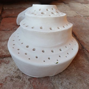 May include: White ceramic ring holder with multiple holes in a spiral design.