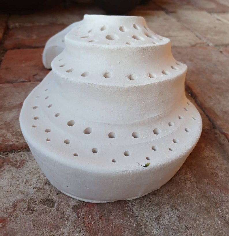May include: White ceramic ring holder with multiple holes in a spiral design.
