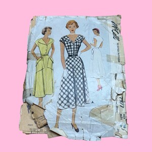 May include: Vintage McCall's dress pattern, featuring illustrations of three dresses. The main dress is a black and white checkered design with a fitted bodice and flared skirt. The pattern is labeled "7977" and includes size information.
