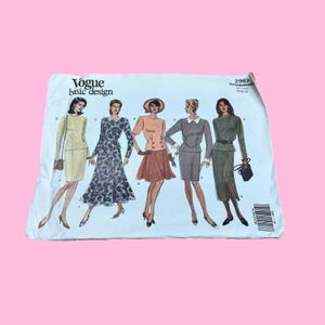 May include: A vintage Vogue Basic Design sewing pattern packet. The packet features illustrations of five different women's outfits, including dresses and suits. The packet is white with the Vogue logo and pattern number 2967.