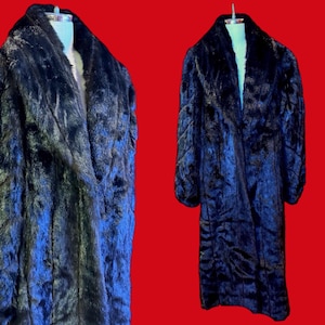 May include: A long, black faux fur coat with a wide collar, displayed on a mannequin. The coat has a plush texture and a classic design, perfect for cold weather. The coat is approximately 55 inches long.