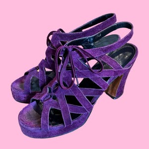 May include: Purple suede platform sandals with a lace-up design and a chunky heel.