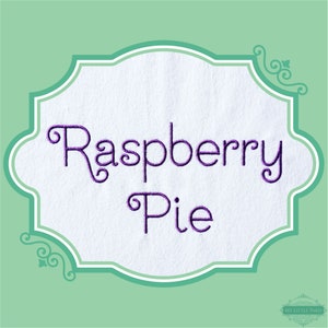 May include: A white label with a purple embroidered design that says "Raspberry Pie" in a decorative font. The label is framed with a decorative border.