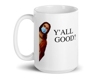 Può includere: Tazza in ceramica bianca con una grafica di Gesù che indossa una maschera facciale blu e il testo "Y'ALL GOOD?"