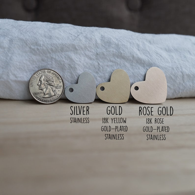 May include: Three heart-shaped metal tags in silver, gold, and rose gold. The tags are labeled "Silver Stainless", "Gold 18k Yellow Gold-Plated Stainless", and "Rose Gold 18k Rose Gold-Plated Stainless".