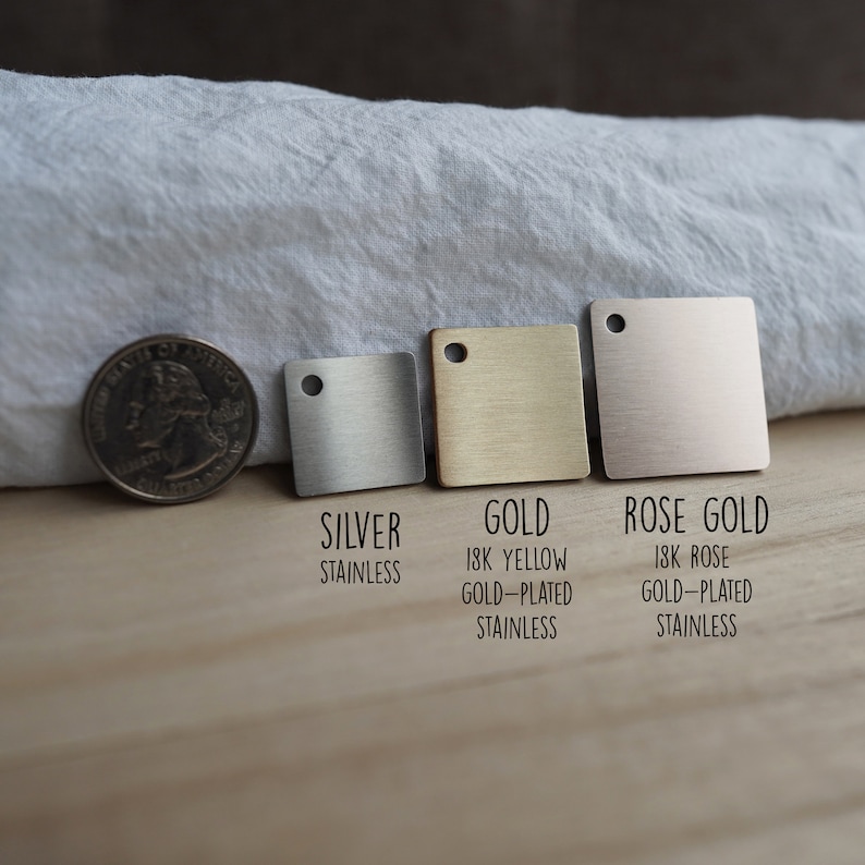 May include: Three square metal samples in silver, gold, and rose gold. The samples are labeled with their respective metal types and descriptions: "Silver Stainless", "Gold 18K Yellow Gold-Plated Stainless", and "Rose Gold 18K Rose Gold-Plated Stainless".
