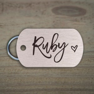May include: Silver dog tag with a black engraved name "Ruby" and a small heart symbol.