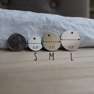 Pode incluir: Tr&ecirc;s etiquetas redondas de metal em tamanhos diferentes, etiquetadas "S", "M" e "L". As etiquetas t&ecirc;m um di&acirc;metro de 0,9 polegadas, 1,1 polegadas e 1,3 polegadas, respetivamente. Uma moeda de 25 centavos de d&oacute;lar americano &eacute; mostrada para compara&ccedil;&atilde;o de tamanho.