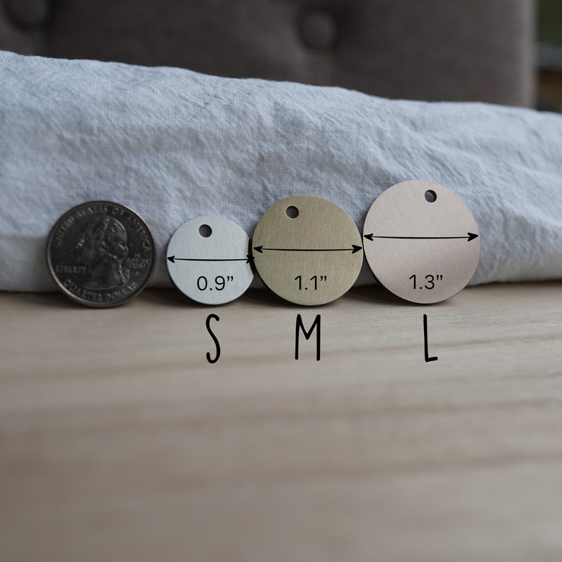 Pode incluir: Tr&ecirc;s etiquetas redondas de metal em tamanhos diferentes, etiquetadas "S", "M" e "L". As etiquetas t&ecirc;m um di&acirc;metro de 0,9 polegadas, 1,1 polegadas e 1,3 polegadas, respetivamente. Uma moeda de 25 centavos de d&oacute;lar americano &eacute; mostrada para compara&ccedil;&atilde;o de tamanho.