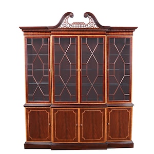 May include: A mahogany wood bookcase with a decorative top and glass doors. The bookcase has four shelves and four drawers. The doors have a diamond-shaped pattern.