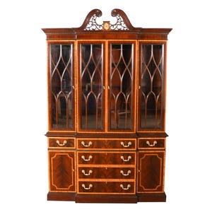 May include: A large, antique wooden cabinet with glass doors and drawers. The cabinet is made of dark wood with lighter wood accents and features ornate detailing, including a decorative top and brass hardware. The glass doors have a lattice design.