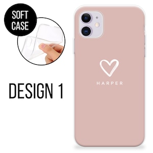May include: A soft phone case in Design 1. The case is a dusty rose color with a white heart graphic and the name "HARPER" printed below. The image also shows a clear, flexible case being held.