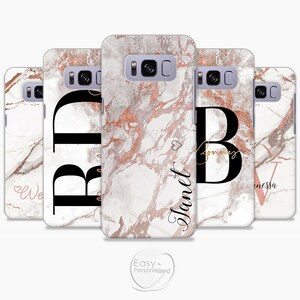 May include: Four personalized phone cases with a white and rose gold marble design. Each case features a black initial and a name in rose gold script. The names are "We", "B", "Janet", and "Vanessa".