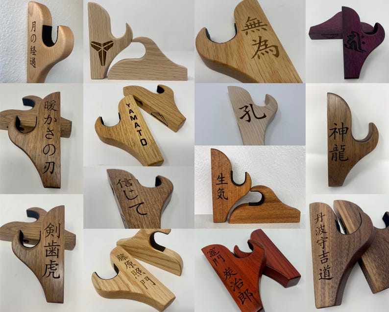 May include: A collection of 12 wooden wall-mounted sword holders with various Japanese kanji characters engraved on them. The holders are made of different types of wood, including light and dark wood, and some are stained in a deep purple color.