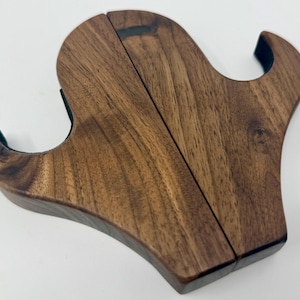 May include: A wooden wall mount with two hooks, made from dark brown walnut wood. The hooks are shaped like a stylized letter S.