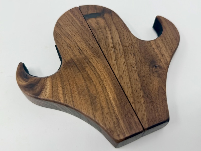 May include: A wooden wall mount with two hooks, made from dark brown walnut wood. The hooks are shaped like a stylized letter S.