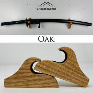 Puede incluir: Un soporte de exhibición de espada de madera hecho de roble. El soporte tiene forma de ola y tiene un forro de fieltro negro para proteger la espada. El soporte está diseñado para sostener una katana u otra espada japonesa.