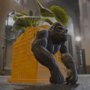 May include: A black gorilla statue with a plant growing out of its back. The gorilla is standing on a yellow planter with a wood-like texture.