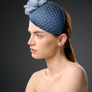 May include: A blue and light blue hat with a flower detail. The hat is made of a mesh fabric and has a rounded shape.