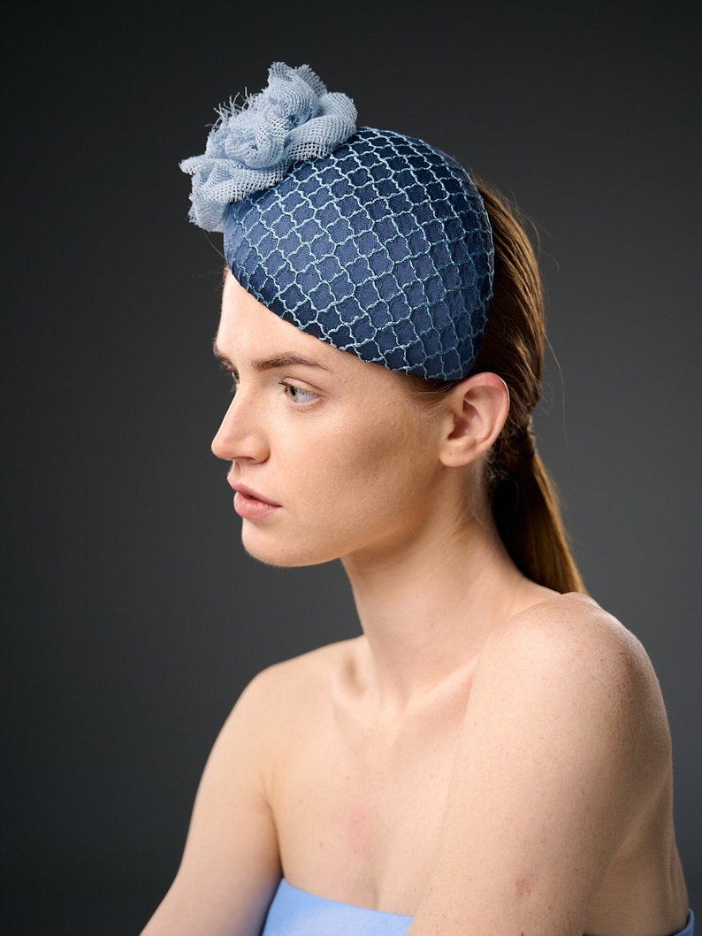 May include: A blue and light blue hat with a flower detail. The hat is made of a mesh fabric and has a rounded shape.