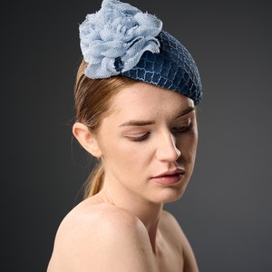 May include: A blue and light blue hat with a flower design. The hat is made of a textured fabric and has a rounded shape.