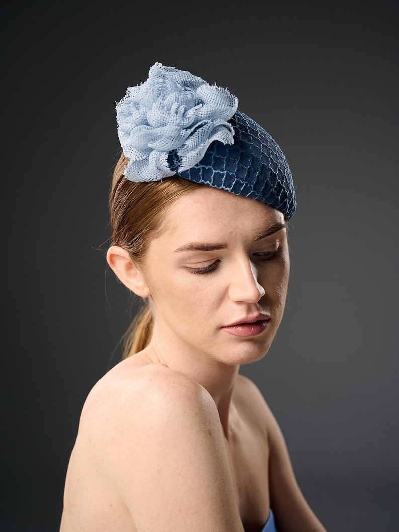 May include: A blue and light blue hat with a flower design. The hat is made of a textured fabric and has a rounded shape.