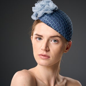 May include: A blue and light blue hat with a flower design. The hat is made of a textured fabric and has a rounded shape.