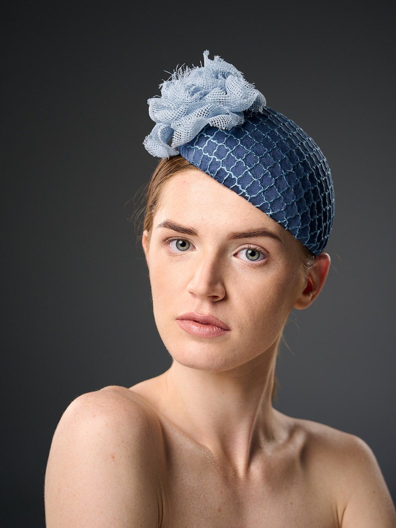 May include: A blue and light blue hat with a flower design. The hat is made of a textured fabric and has a rounded shape.