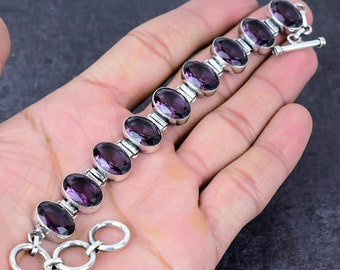 May include: A silver bracelet with a chain and a clasp. The bracelet is adorned with eight oval-shaped amethyst gemstones.